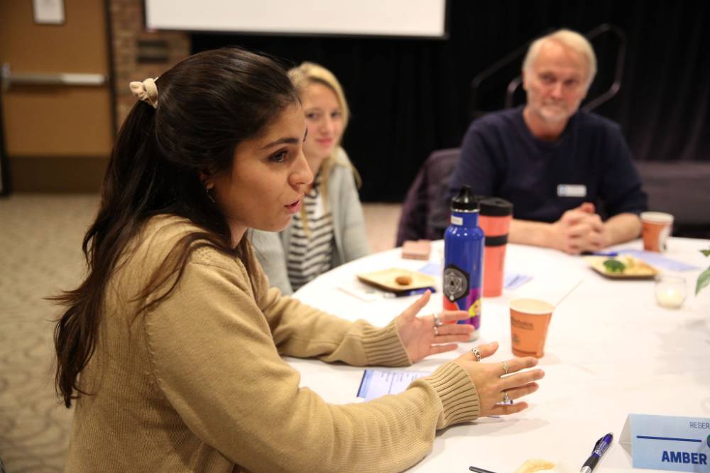 A student speaks to attendees at a round table discussion